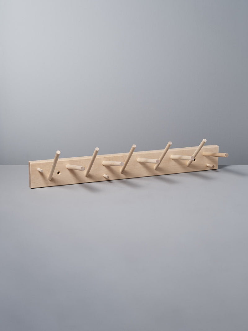 The Multihanger Rack – Birch by Iris Hantverk showcases five pegs, beautifully installed on a light gray wall, and crafted from untreated birch for a natural finish.
