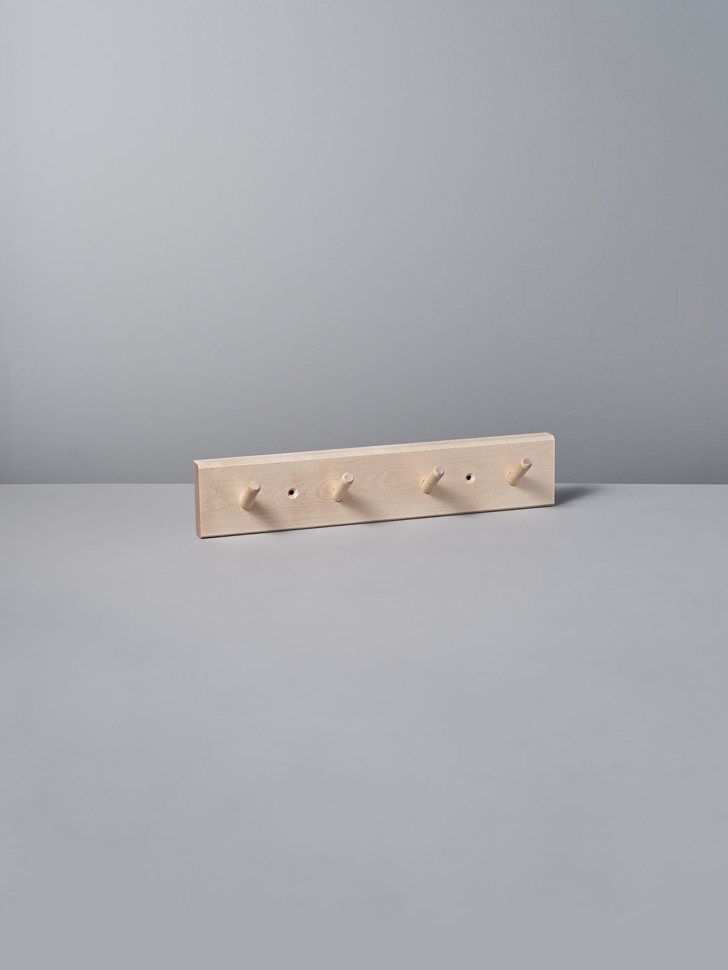 The Birchwood Peg Rail – 4 Hook by Iris Hantverk features four Shaker-inspired pegs mounted on an untreated birch surface, set against a light grey background.