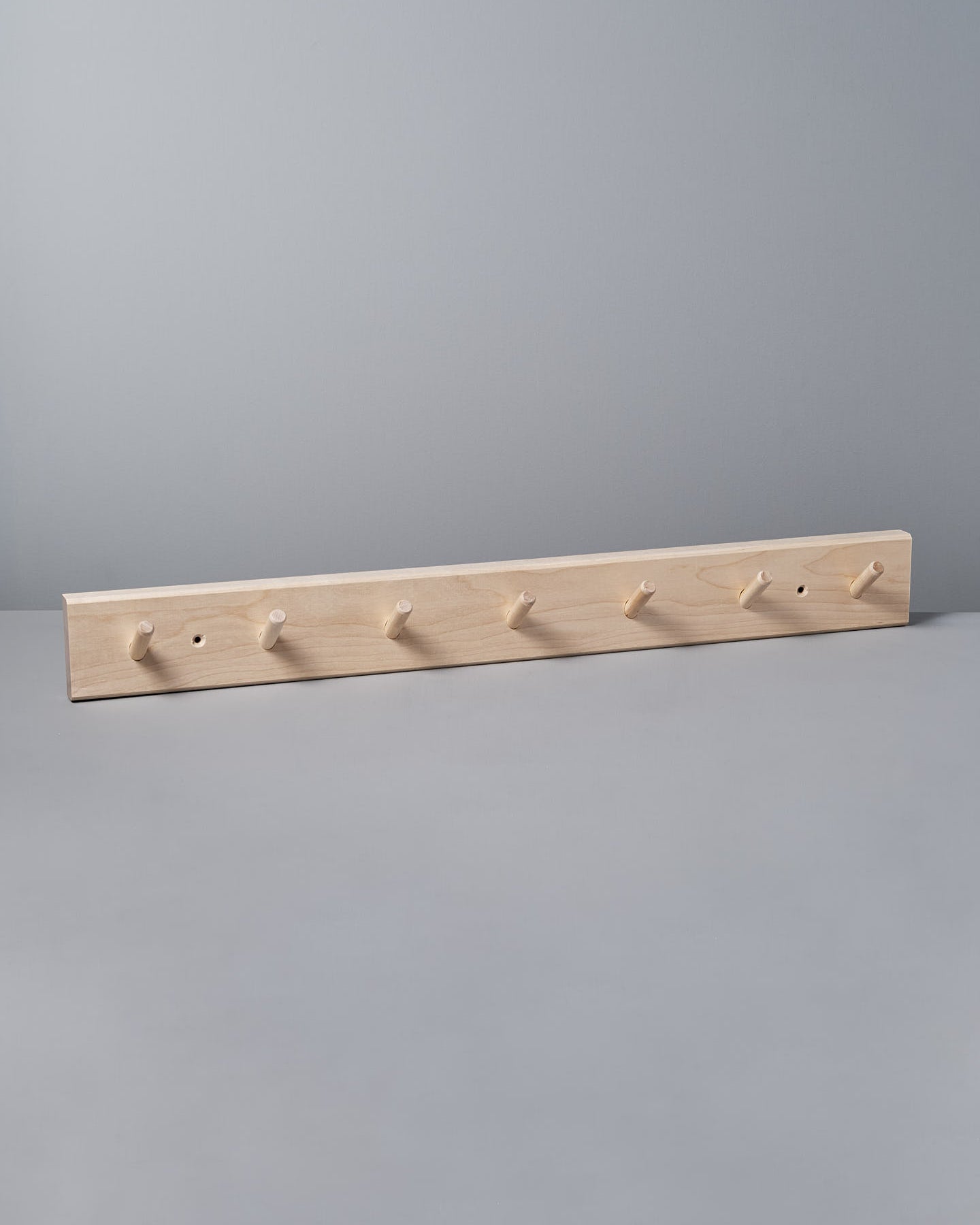 The gray wall is elegantly adorned with an Iris Hantverk Birchwood Peg Rail – 7 Hook, a Shaker-inspired design that helps organize space effortlessly.