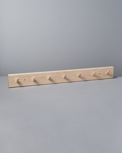 The gray wall is elegantly adorned with an Iris Hantverk Birchwood Peg Rail – 7 Hook, a Shaker-inspired design that helps organize space effortlessly.