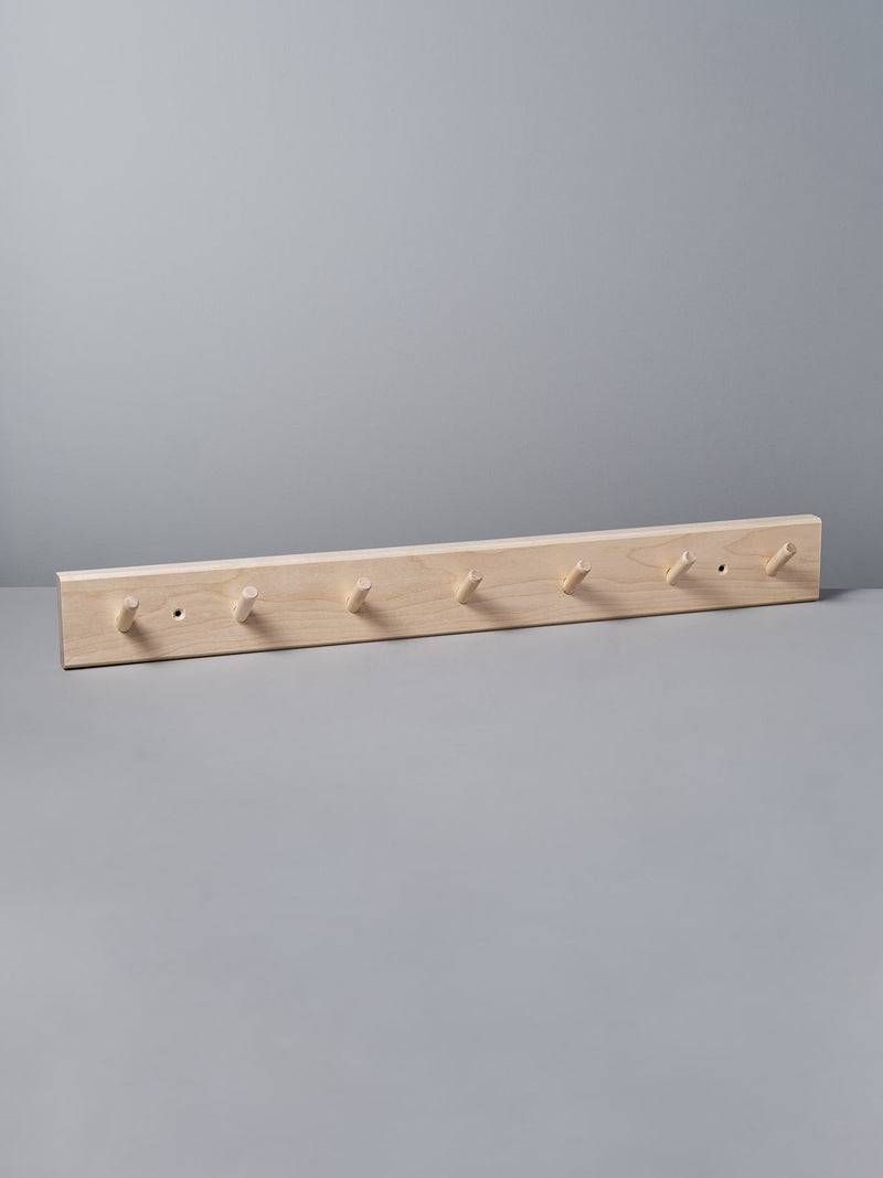 The gray wall is elegantly adorned with an Iris Hantverk Birchwood Peg Rail – 7 Hook, a Shaker-inspired design that helps organize space effortlessly.