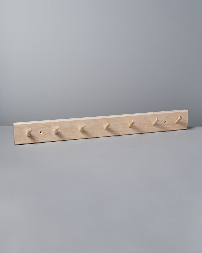The gray wall is elegantly adorned with an Iris Hantverk Birchwood Peg Rail – 7 Hook, a Shaker-inspired design that helps organize space effortlessly.