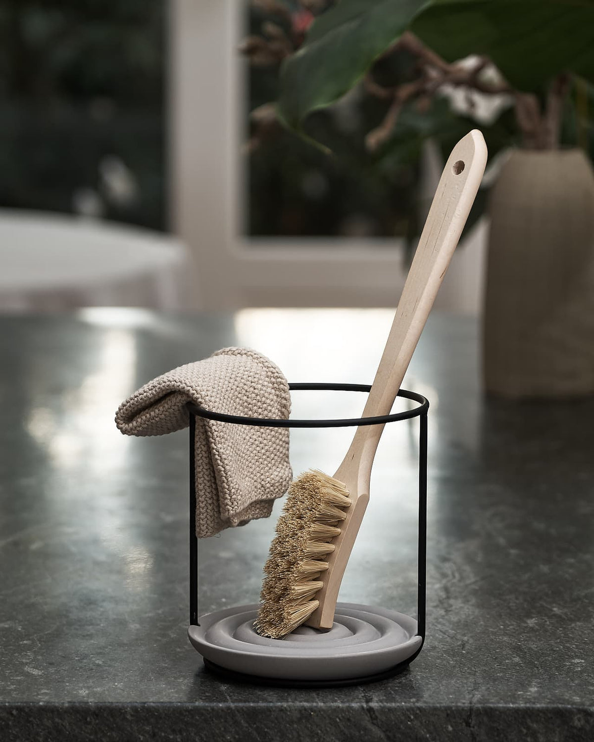 An Iris Hantverk Dish Brush Holder on top of a kitchen bench.