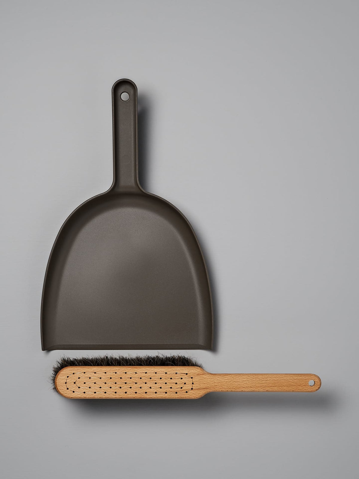 A Dustpan &amp; Brush Set – Umber from Iris Hantverk lies on a grey surface.