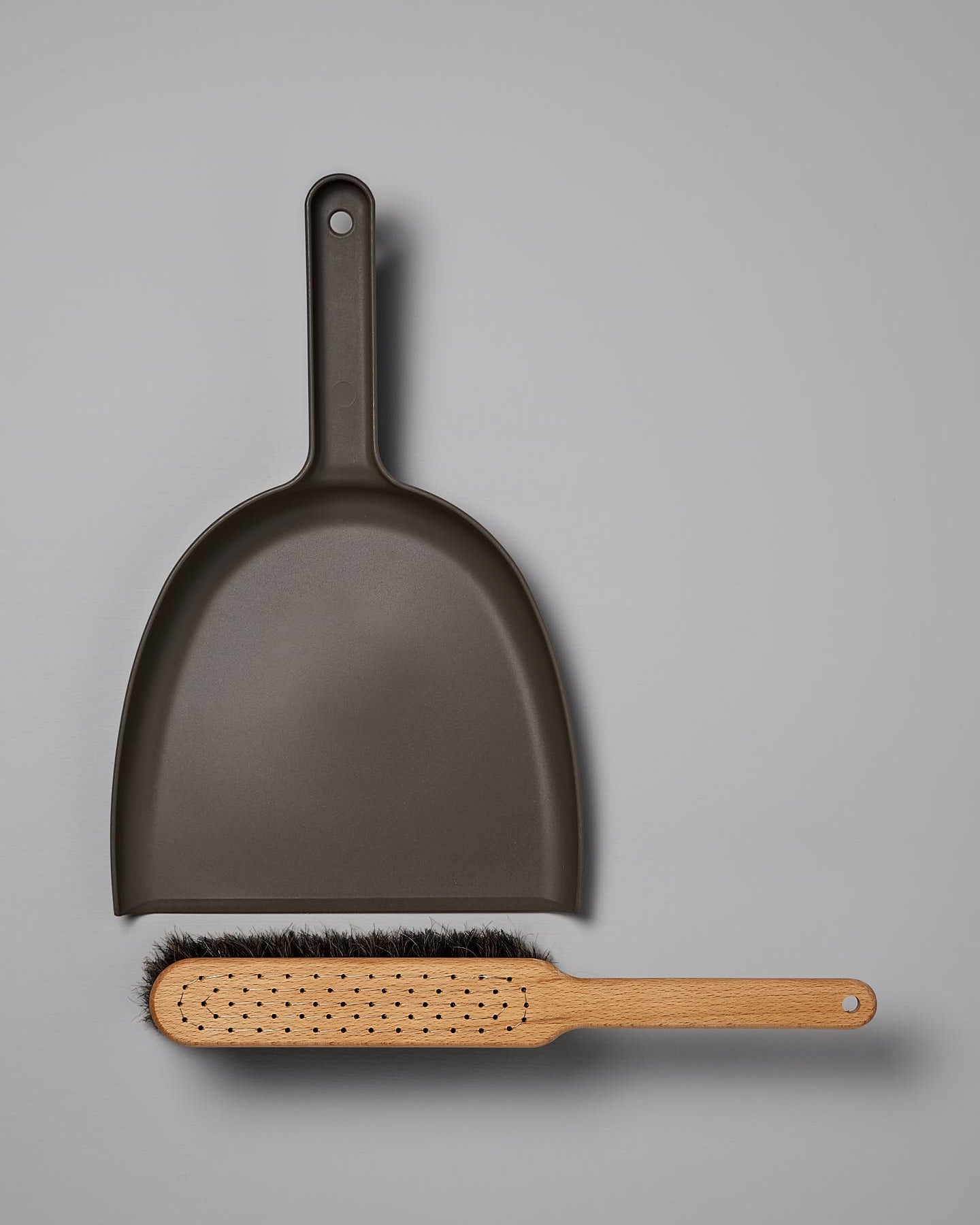 A Dustpan & Brush Set – Umber from Iris Hantverk lies on a grey surface.