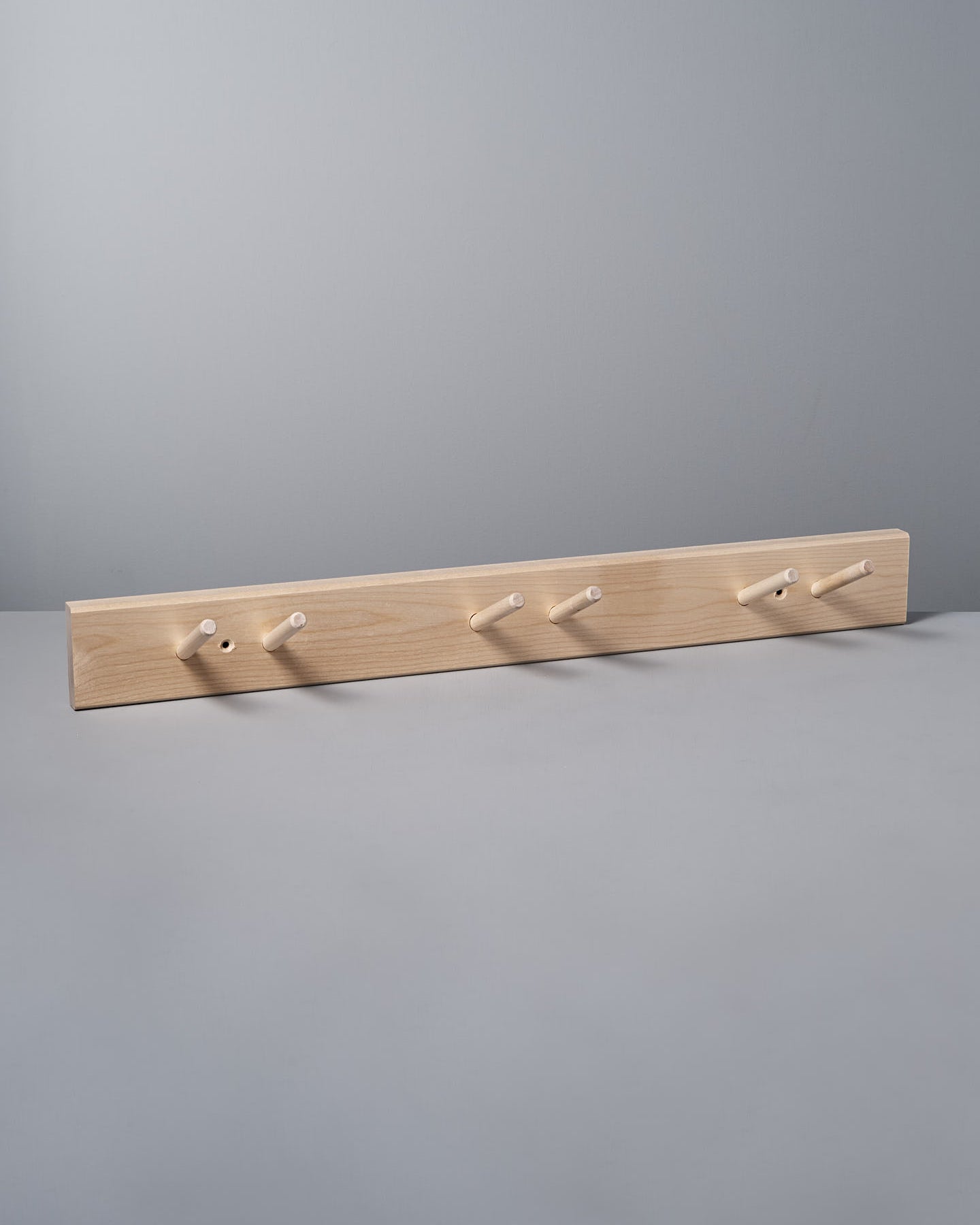 The Birchwood Garden Tool Hanger by Iris Hantverk showcases a Shaker-inspired design with five pegs against a gray background, providing both style and functionality.