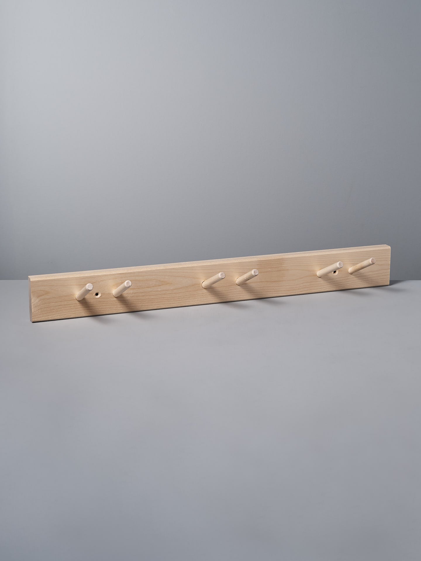 The Birchwood Garden Tool Hanger by Iris Hantverk showcases a Shaker-inspired design with five pegs against a gray background, providing both style and functionality.