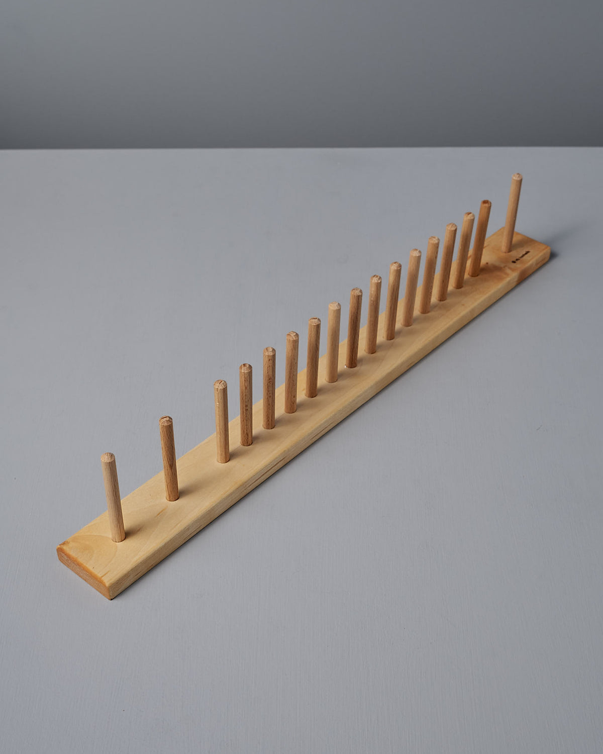 The Knopplist Hook Rack by Iris Hantverk is an elegant utensil holder, crafted from oiled maple, and features multiple vertical pegs on a flat surface. It is perfect for organizing kitchen brushes or other utensils with style and efficiency.