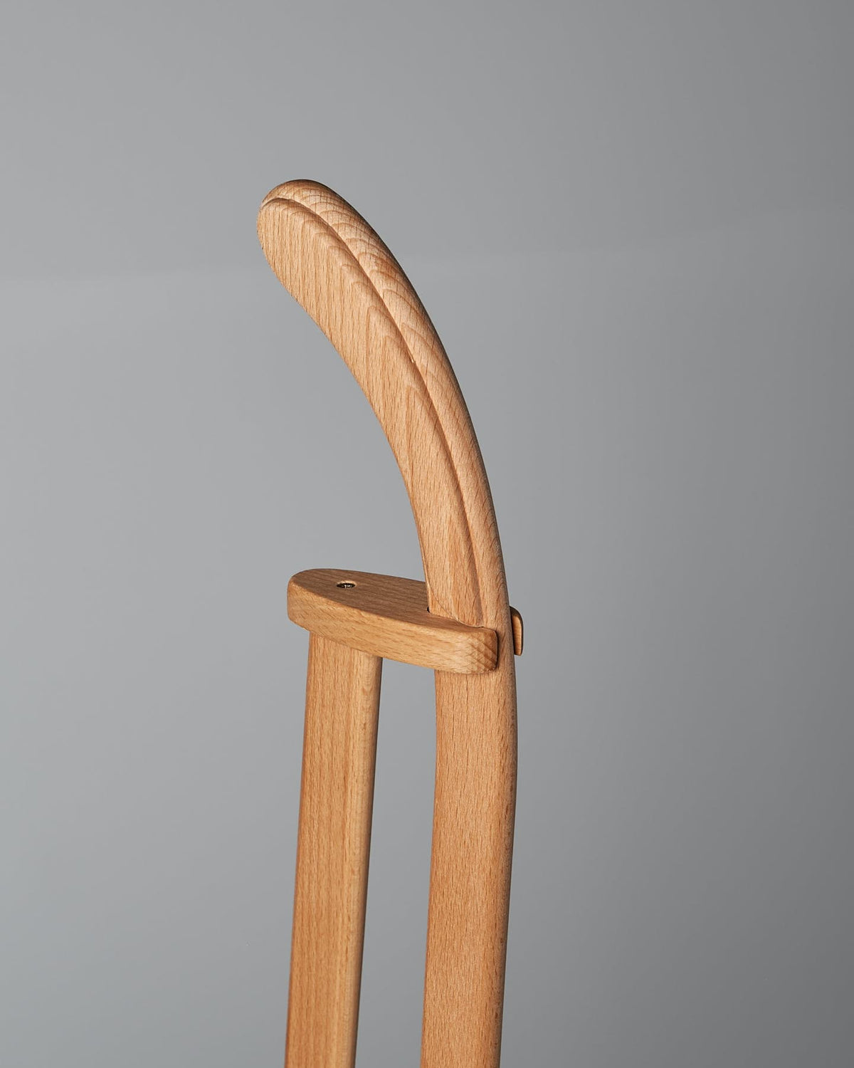 Close-up of the curved wooden handle of a Long Handled Dustpan & Brush Set – Moss Green by Iris Hantverk, crafted with precision reminiscent of a horsehair brush, against a grey background.