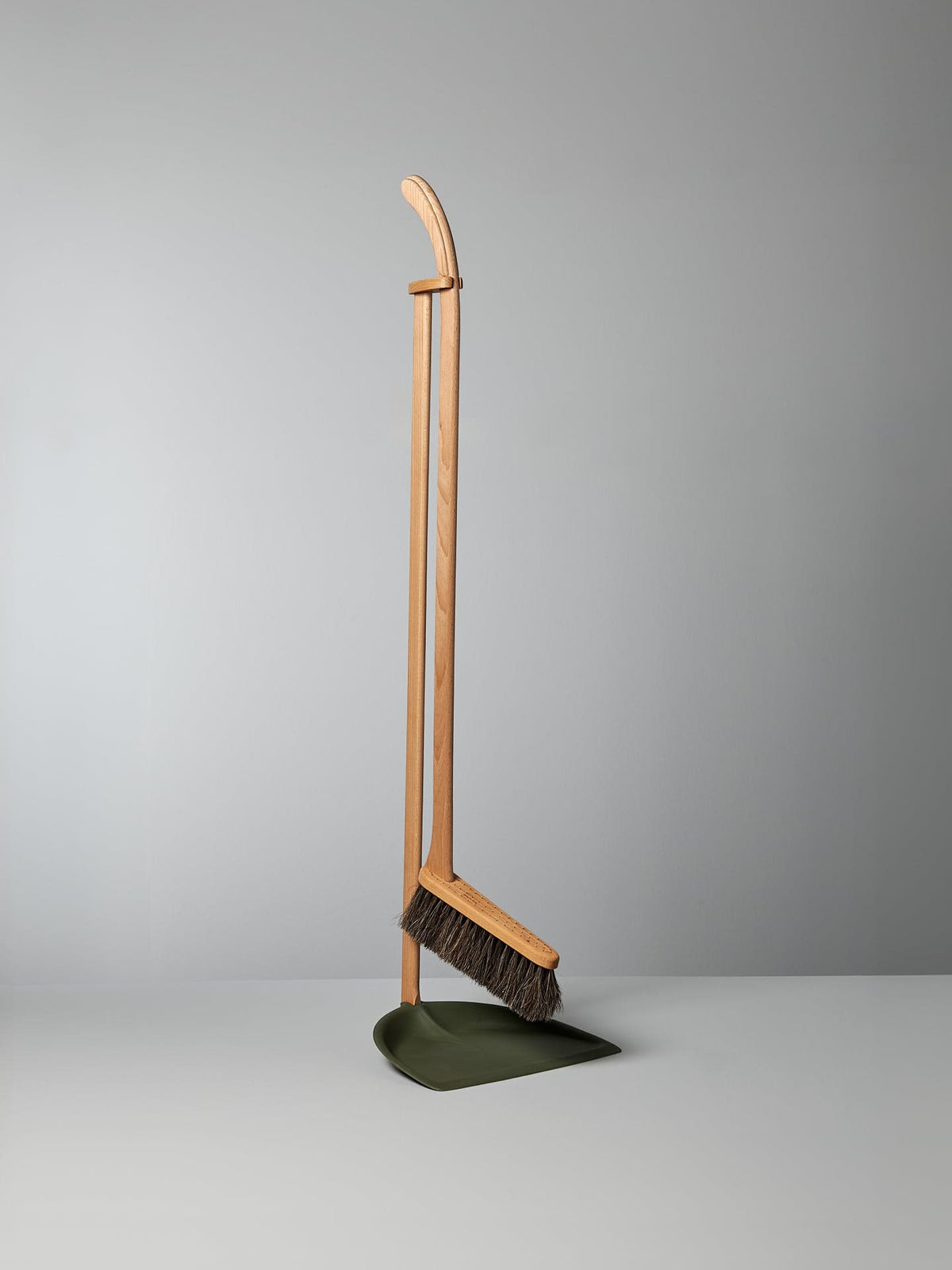 A Long Handled Dustpan &amp; Brush Set – Moss Green from Iris Hantverk stands upright next to a green bio-polyethylene dustpan, both set against a plain gray background.