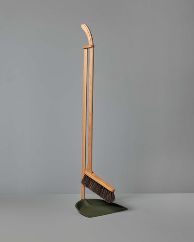 A Long Handled Dustpan & Brush Set – Moss Green from Iris Hantverk stands upright next to a green bio-polyethylene dustpan, both set against a plain gray background.