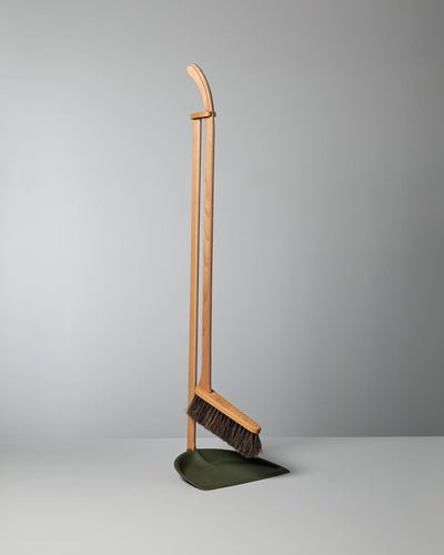 A Long Handled Dustpan & Brush Set – Moss Green from Iris Hantverk stands upright next to a green bio-polyethylene dustpan, both set against a plain gray background.