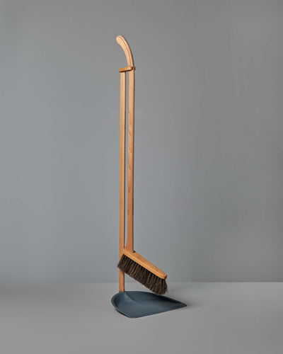 A Long Handled Dustpan & Brush Set standing upright against a plain gray background. 
