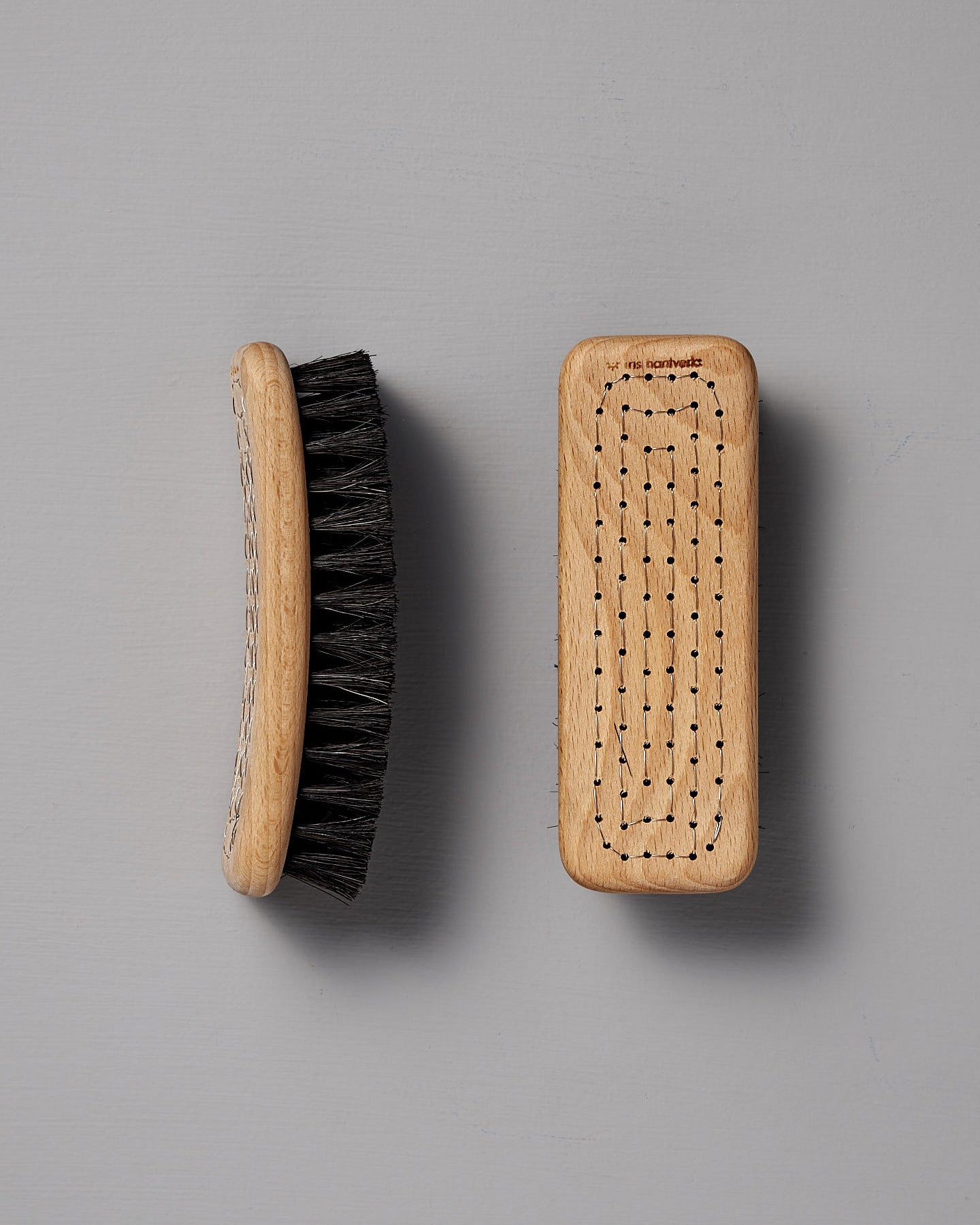 Two Iris Hantverk Shoe Brushes made from beech wood and featuring horse hair bristles, one viewed from the side and the other from the top, set against a gray background.