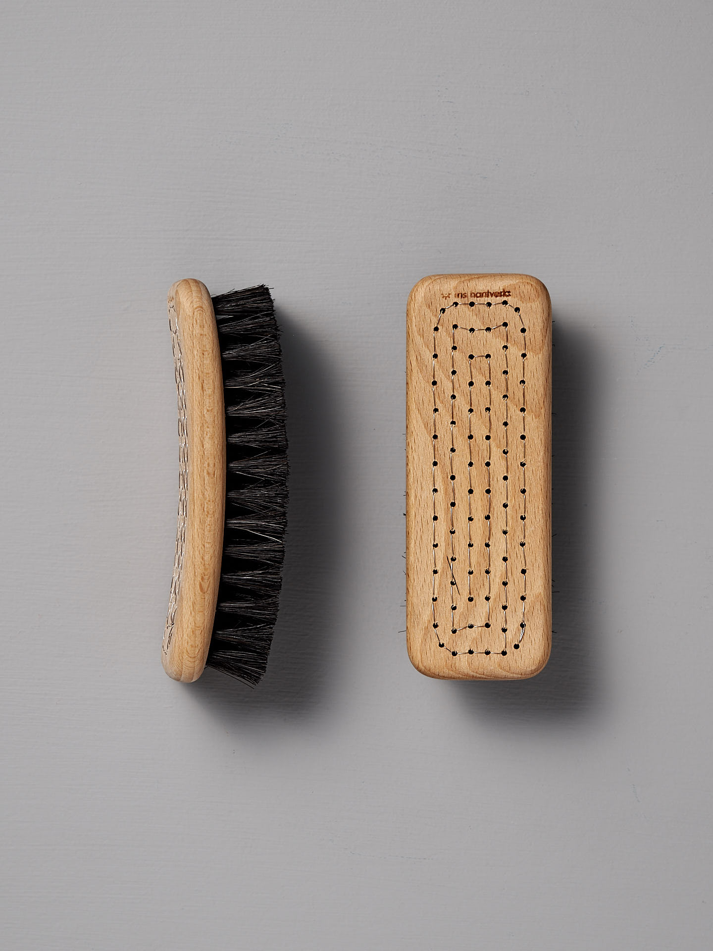 Two Iris Hantverk Shoe Brushes made from beech wood and featuring horse hair bristles, one viewed from the side and the other from the top, set against a gray background.