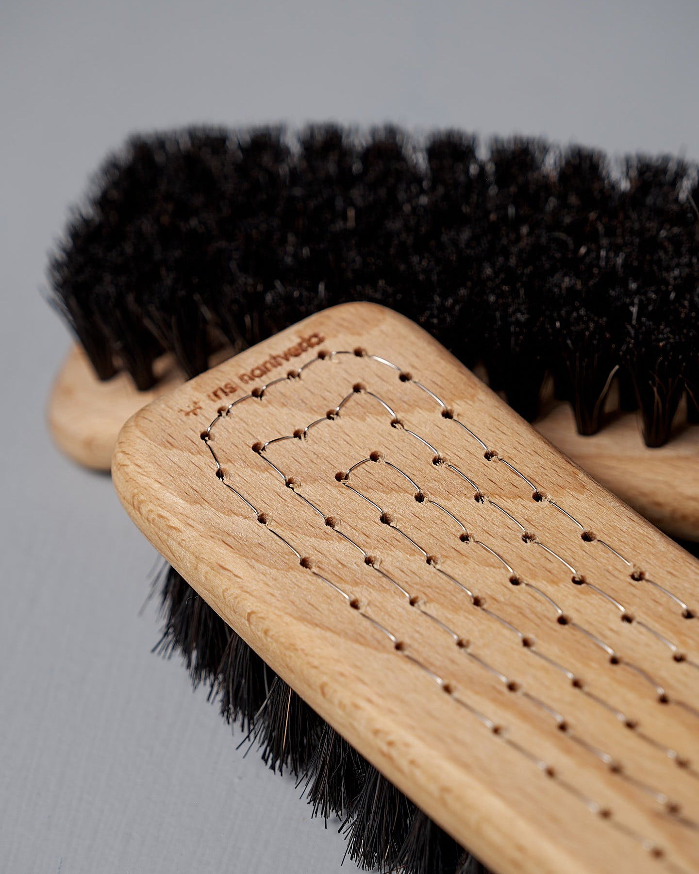 Two Iris Hantverk Shoe Brushes made from beech wood and featuring horse hair bristles, one viewed from the side and the other from the top, set against a gray background.