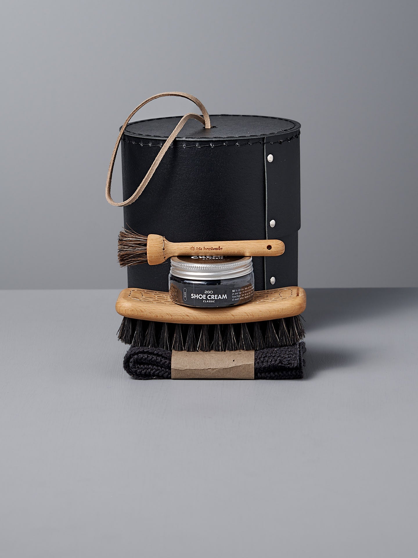 Iris Hantverk's Shoe Care Kit includes a stylish black leather case, Black Shoe Polish, two wooden shoe brushes, and a black cloth on a gray surface.