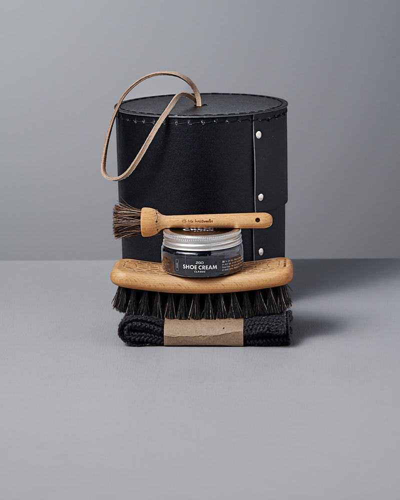 Iris Hantverk's Shoe Care Kit includes a stylish black leather case, Black Shoe Polish, two wooden shoe brushes, and a black cloth on a gray surface.
