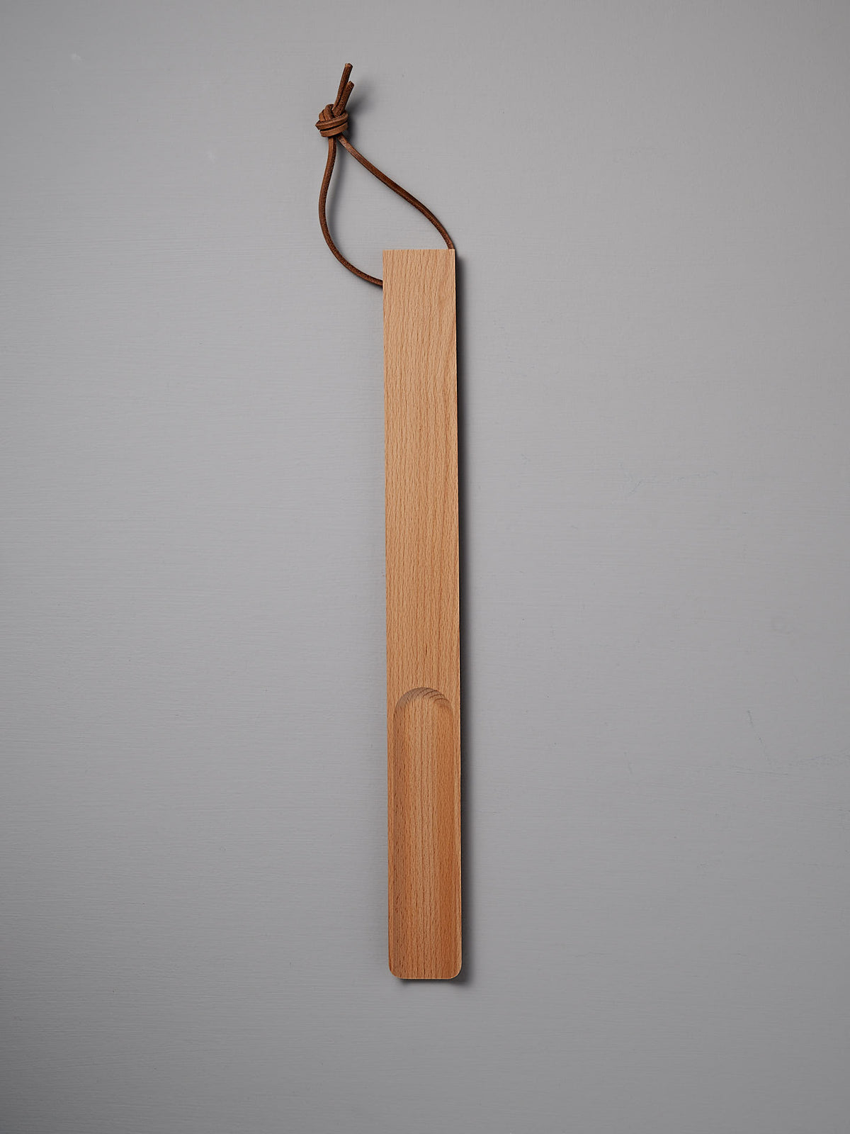 The Iris Hantverk Shoe Horn – Short ⋄ Long, featuring an oiled beech finish and a leather loop for hanging, is showcased on a gray background.