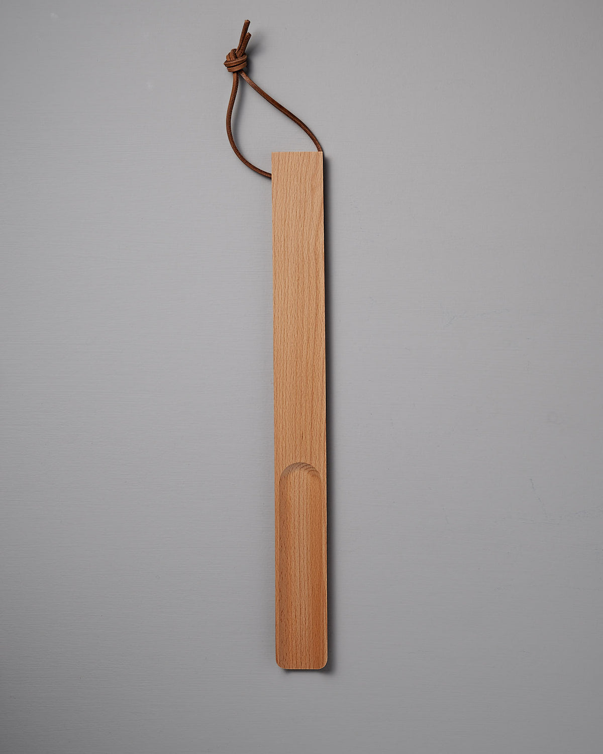 The Iris Hantverk Shoe Horn – Short ⋄ Long, featuring an oiled beech finish and a leather loop for hanging, is showcased on a gray background.