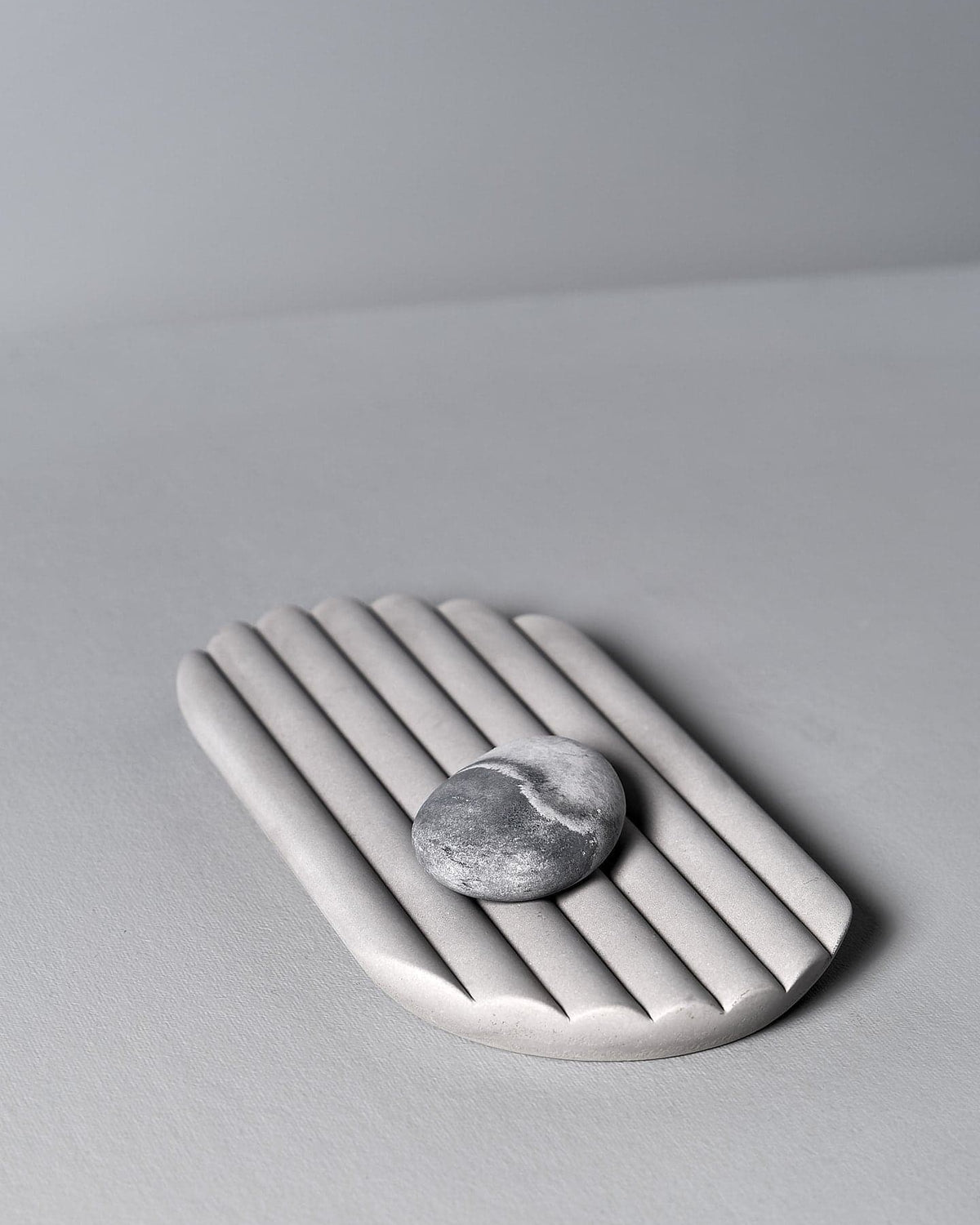 An Iris Hantverk Concrete Tray with a stone on it.
