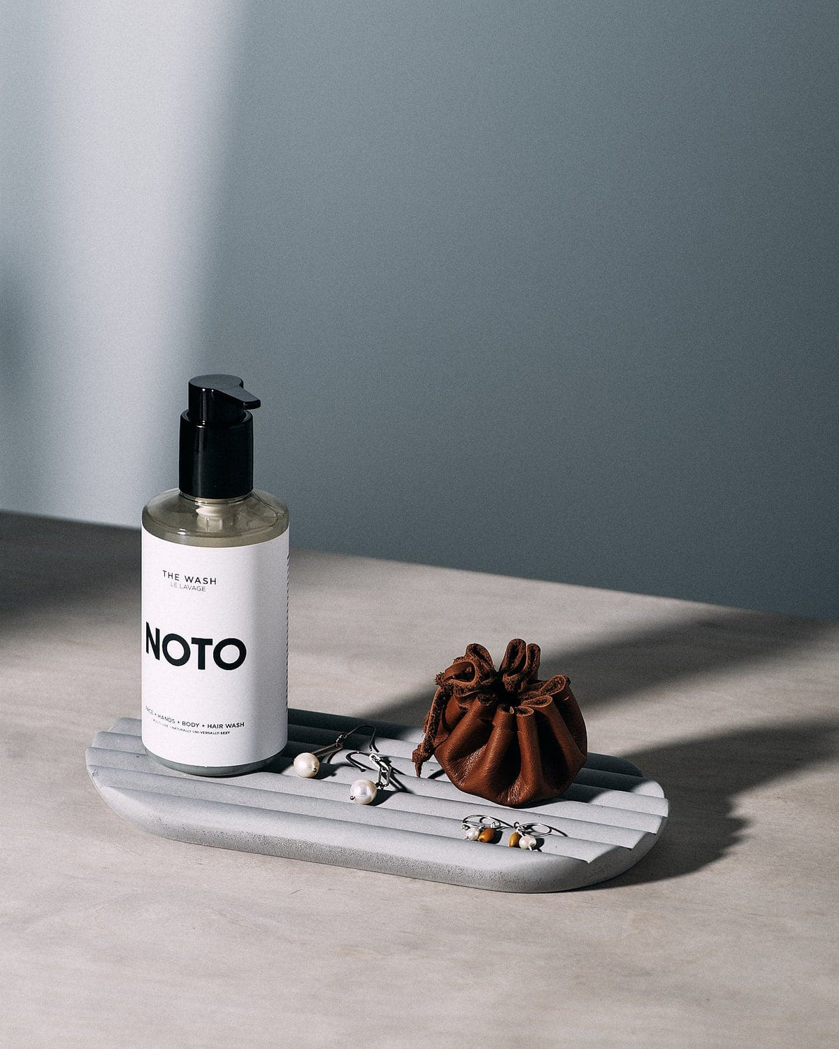 A bottle of Iris Hantverk noto soap sitting on a Concrete Tray.