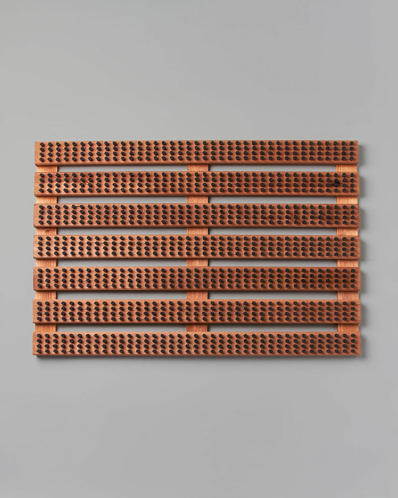 A rectangular panel of brown acoustic tiles with a ribbed texture and perforations, elegantly enhanced by its Beechwood base, is mounted on a light gray wall. Featuring quality craftsmanship reminiscent of the Iris Hantverk brand's Wooden Doormat with Bristles – Standard.