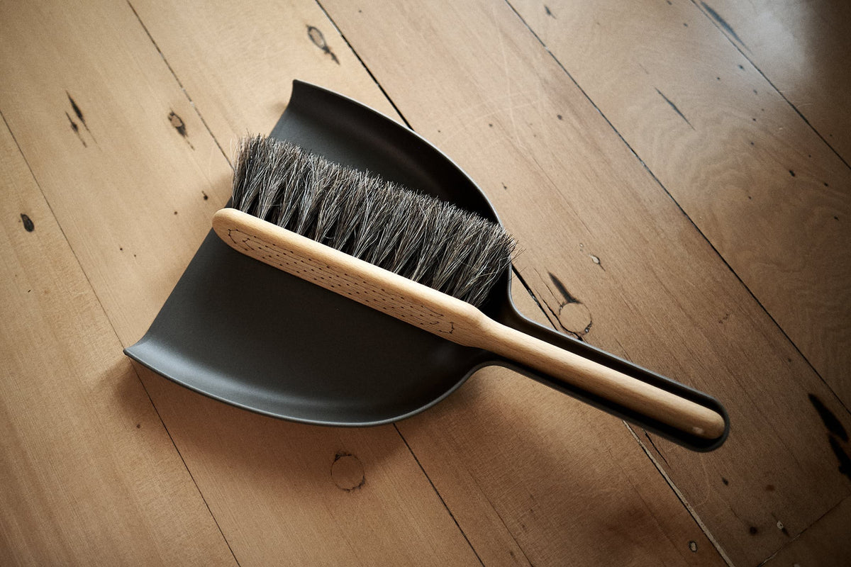 The Dustpan &amp; Brush Set – Umber by Iris Hantverk lies on a wooden floor.