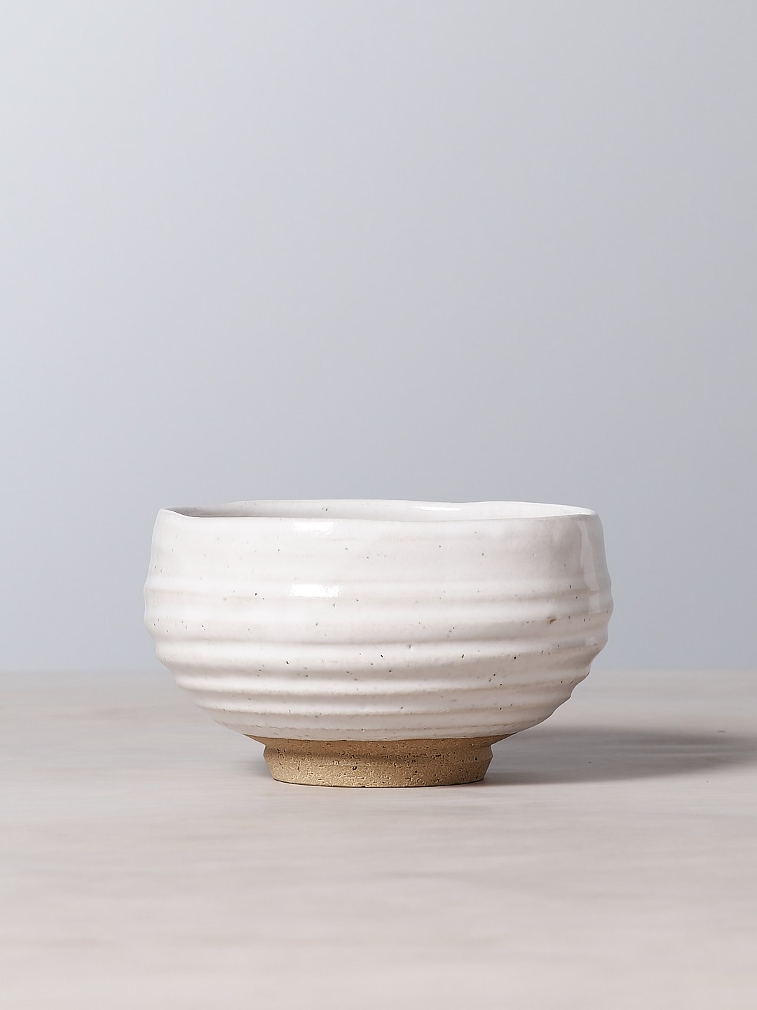 A Ridged Bowl – White from Jino Ceramic Studio sitting on top of a table.