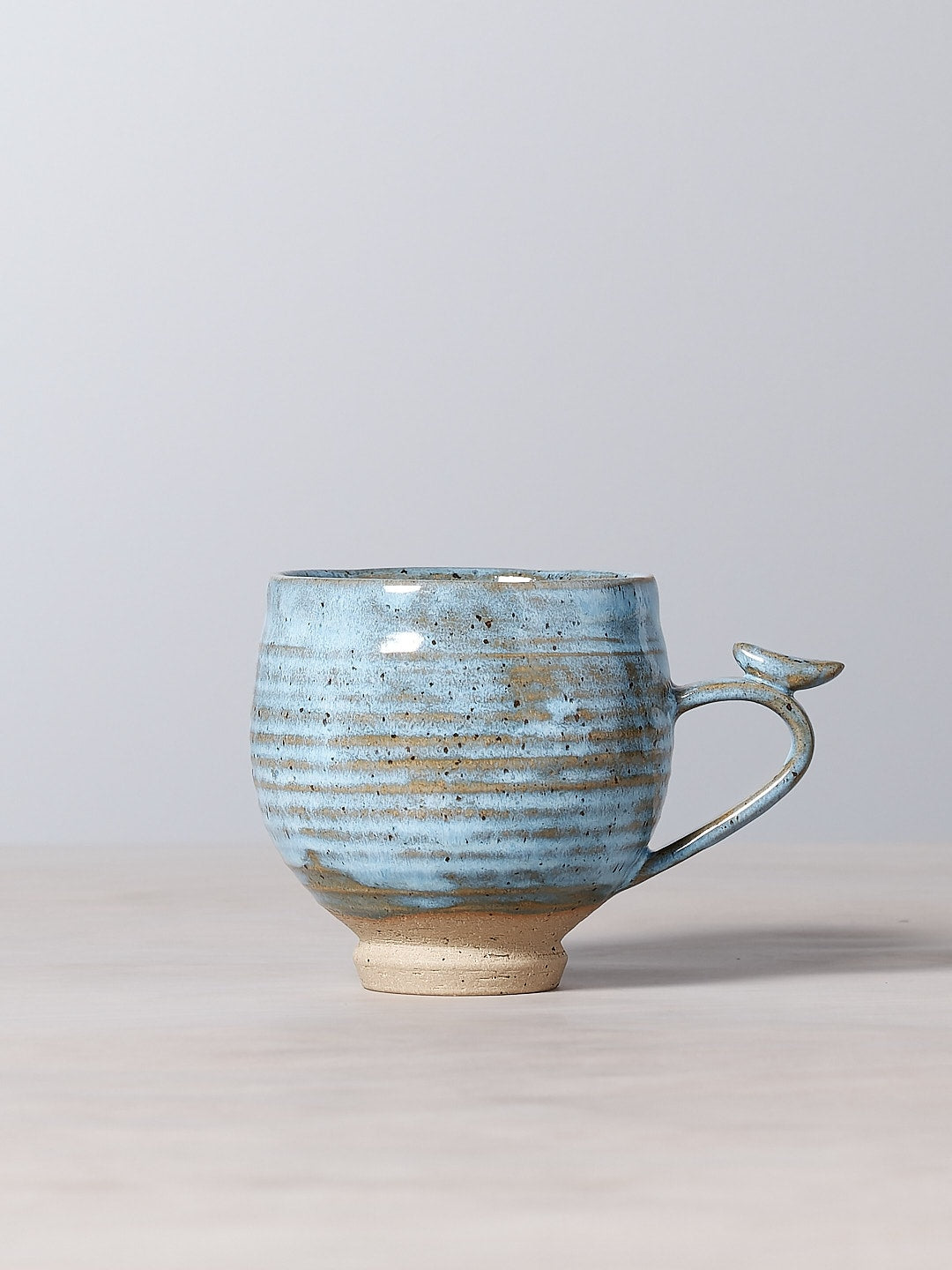 A Jino Ceramic Studio Bird Handle Cup - Sky Blue sitting on top of a table in New Zealand.
