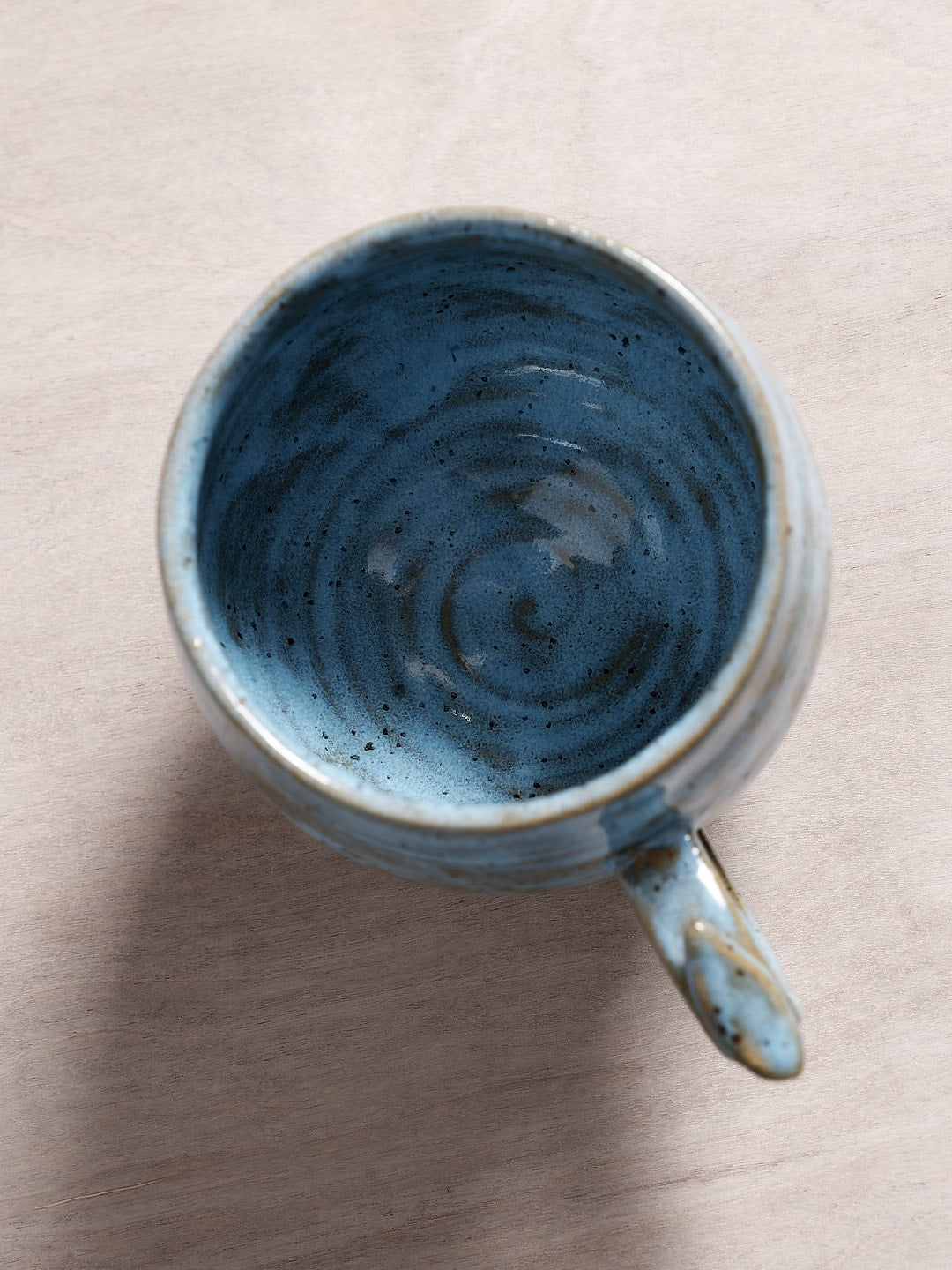 A Bird Handle Cup - Sky Blue from Jino Ceramic Studio sitting on top of a wooden table.