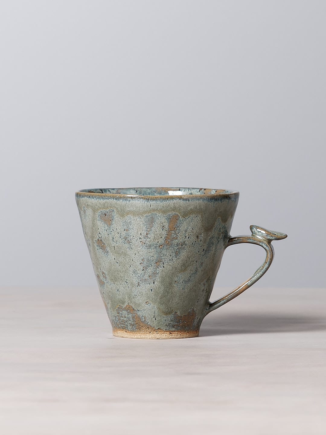 A Bird Handle Mug – Green Tea from Jino Ceramic Studio, with a bird on it, sitting on top of a table, perfect for tea-drinking.