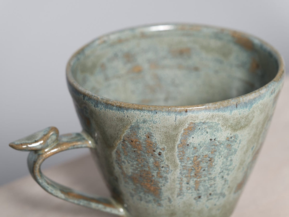 A Bird Handle Mug – Green Tea, perfect for tea-drinking, sitting on a wooden table. (Brand: Jino Ceramic Studio)