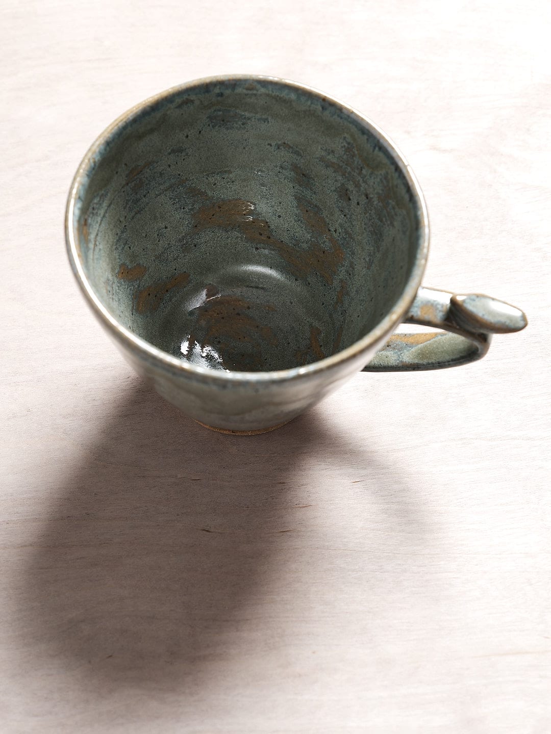 A Bird Handle Mug – Green Tea by Jino Ceramic Studio on a wooden table.