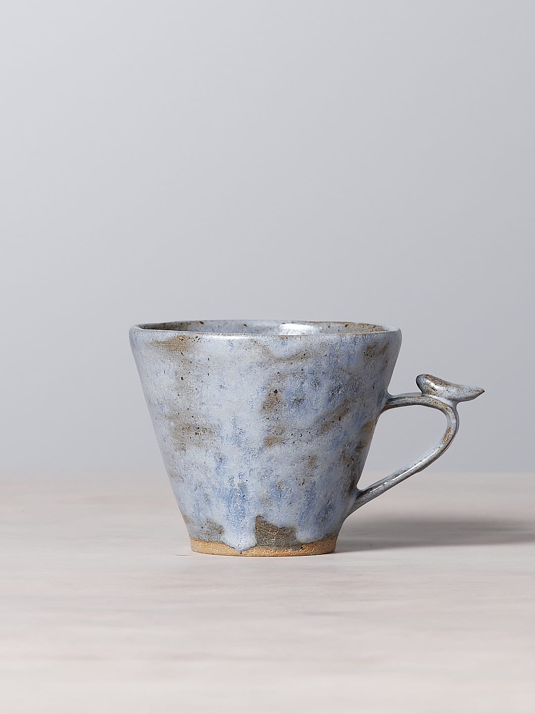 A Bird Handle Mug – Kōkako from Jino Ceramic Studio, sitting on a table.