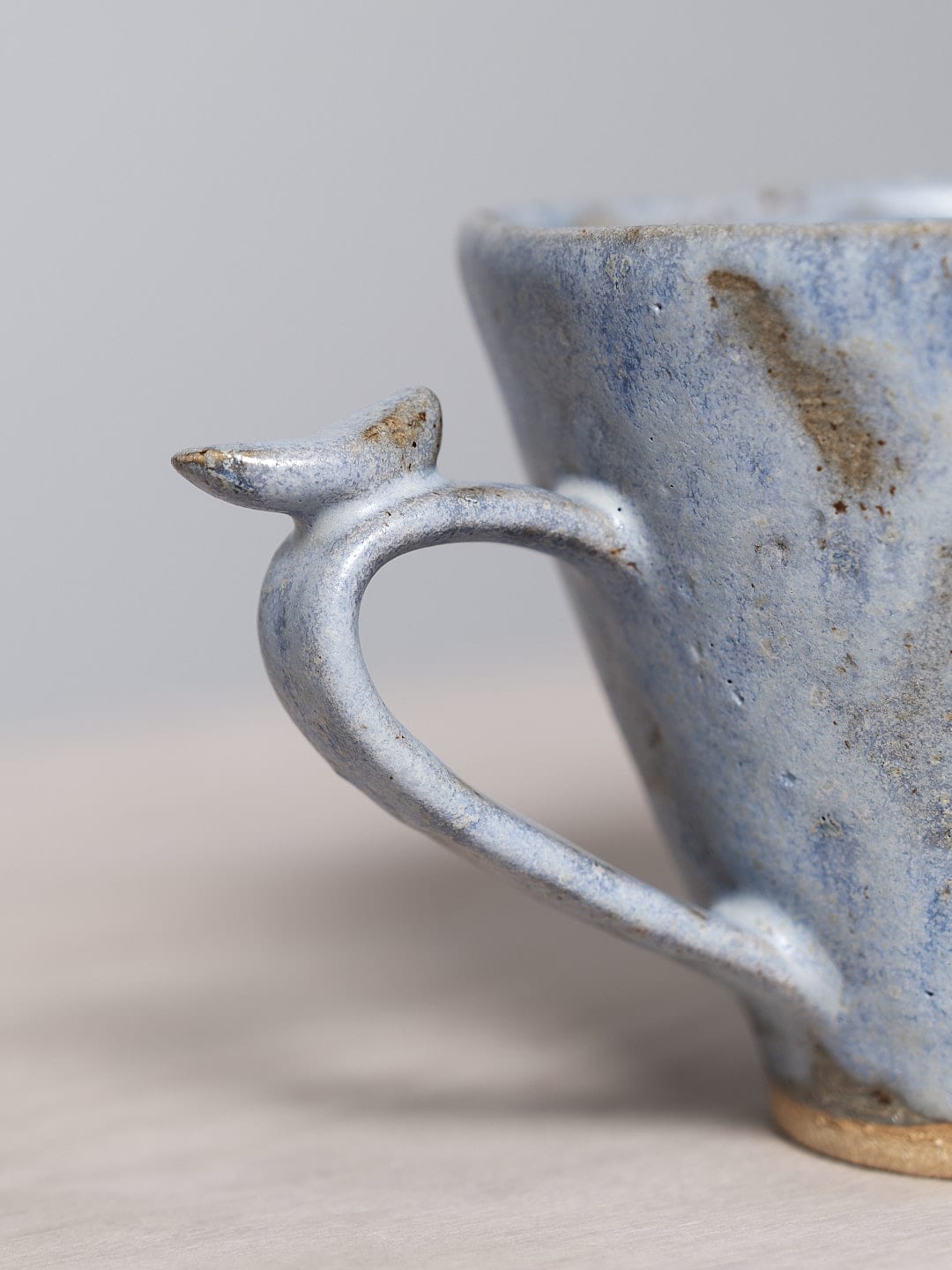 A blue Bird Handle Mug - Kōkako from Jino Ceramic Studio on a table.