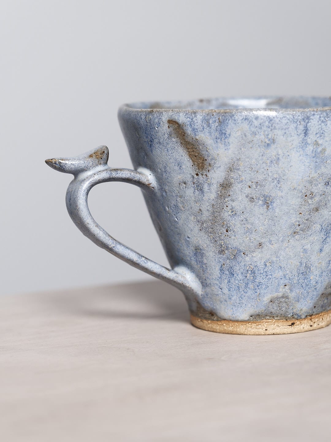 A Bird Handle Mug – Kōkako by Jino Ceramic Studio sitting on a table.