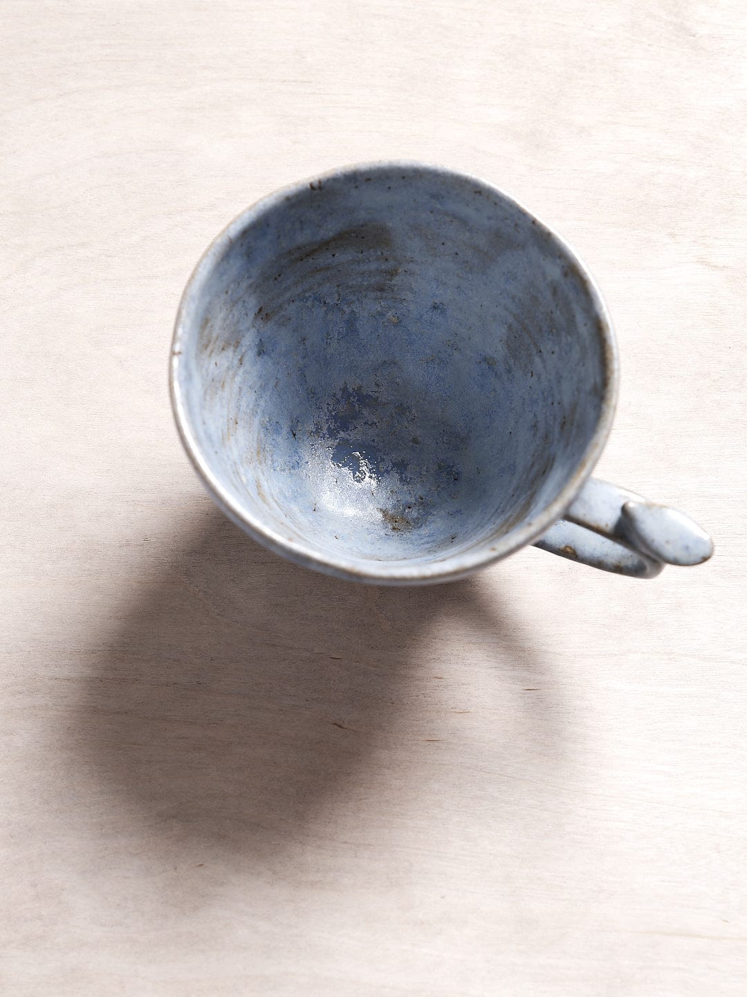 A blue Kōkako Bird Handle Mug from Jino Ceramic Studio sitting on top of a wooden surface.