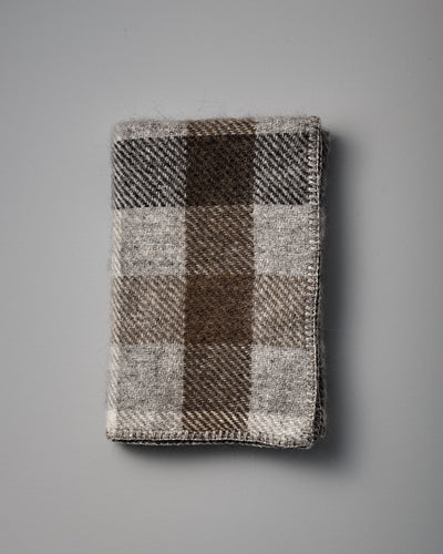 A Gotland Wool Baby Throw – Multi Grey, featuring a classic brown, gray, and beige plaid pattern inspired by timeless Klippan of Sweden designs, is displayed on a plain gray surface.