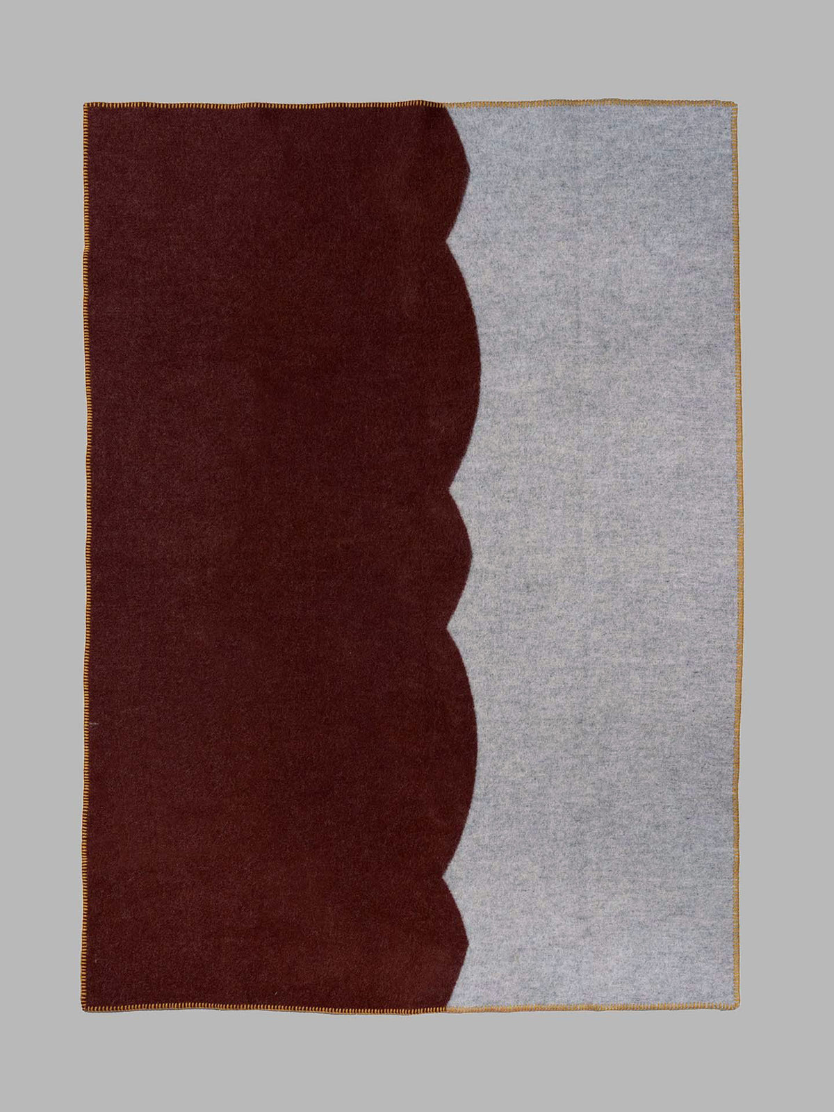 A rectangular area rug with a modern color-blocked design, featuring a deep dark brown section on the left and a light gray heathered section on the right, divided by a scalloped wavy edge.