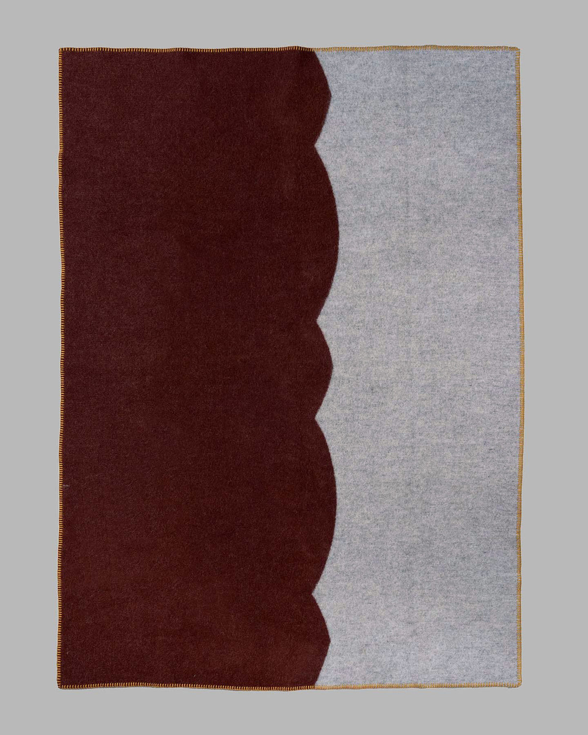 A rectangular area rug with a modern color-blocked design, featuring a deep dark brown section on the left and a light gray heathered section on the right, divided by a scalloped wavy edge.