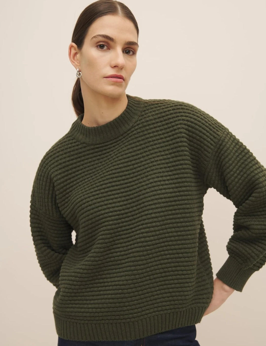 Woman posing in a Kowtow Bubble Jumper – Khaki Marle with balloon sleeves and a neutral background.