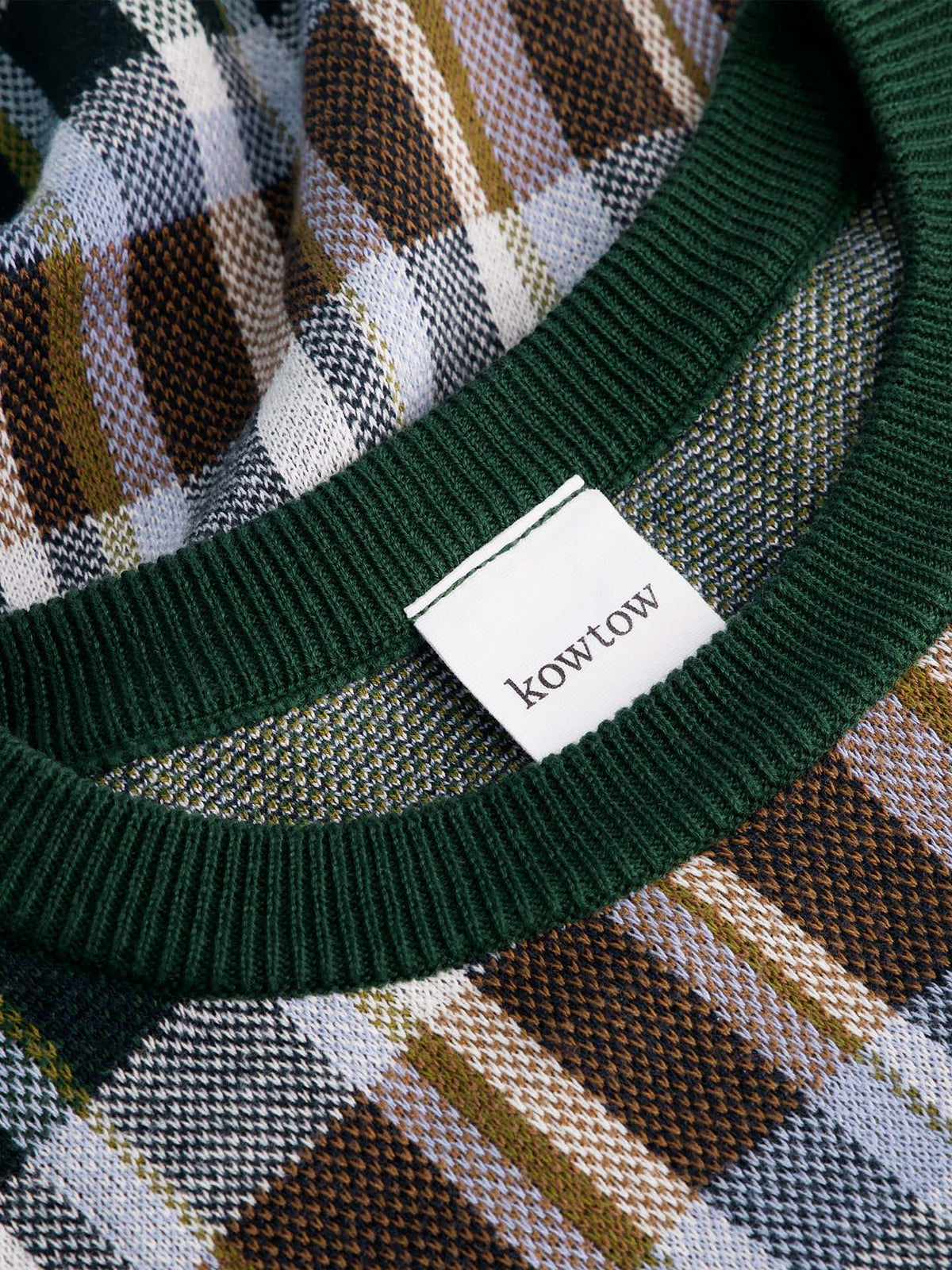 Close-up of the Chequered Tee – Forest: an oversized green, brown, and white plaid top with a green ribbed collar, "Kowtow" label, and drop shoulder sleeves for a relaxed fit.