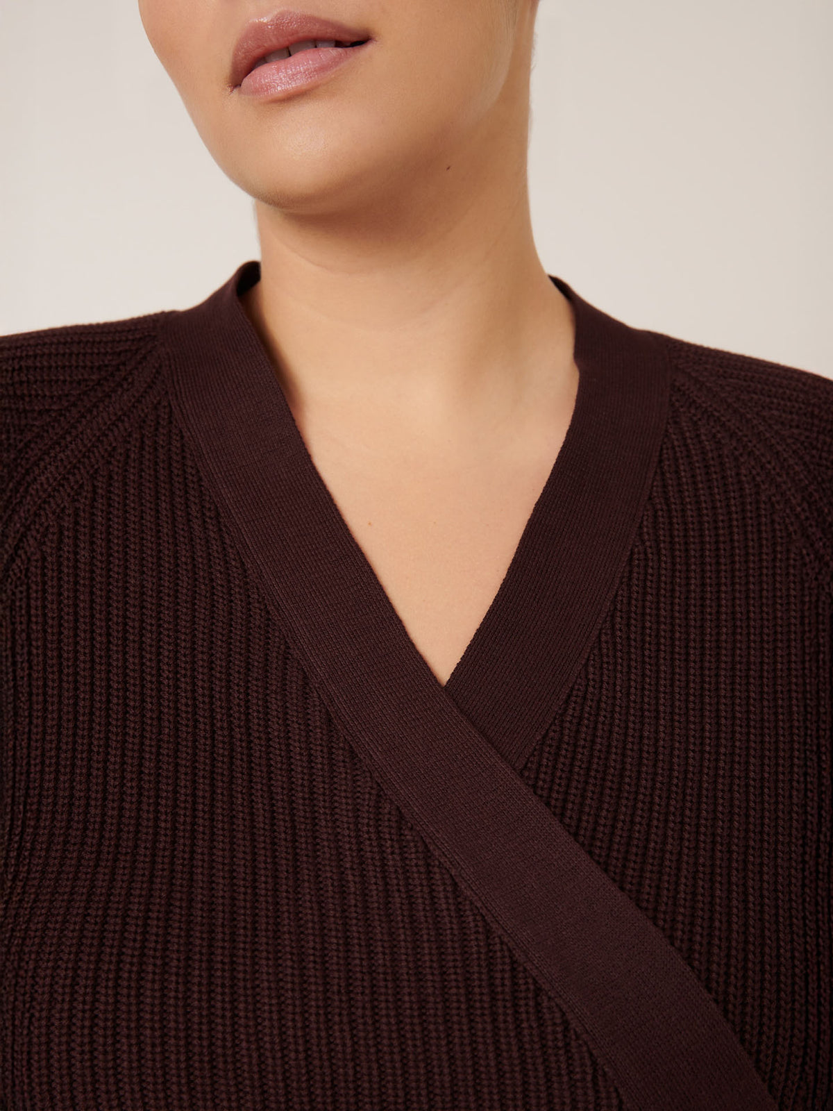 Model wears the Kowtow Composure Cardigan in Mahogany; photo highlights the ribbed knit neckline and upper torso, with only part of the mouth visible.
