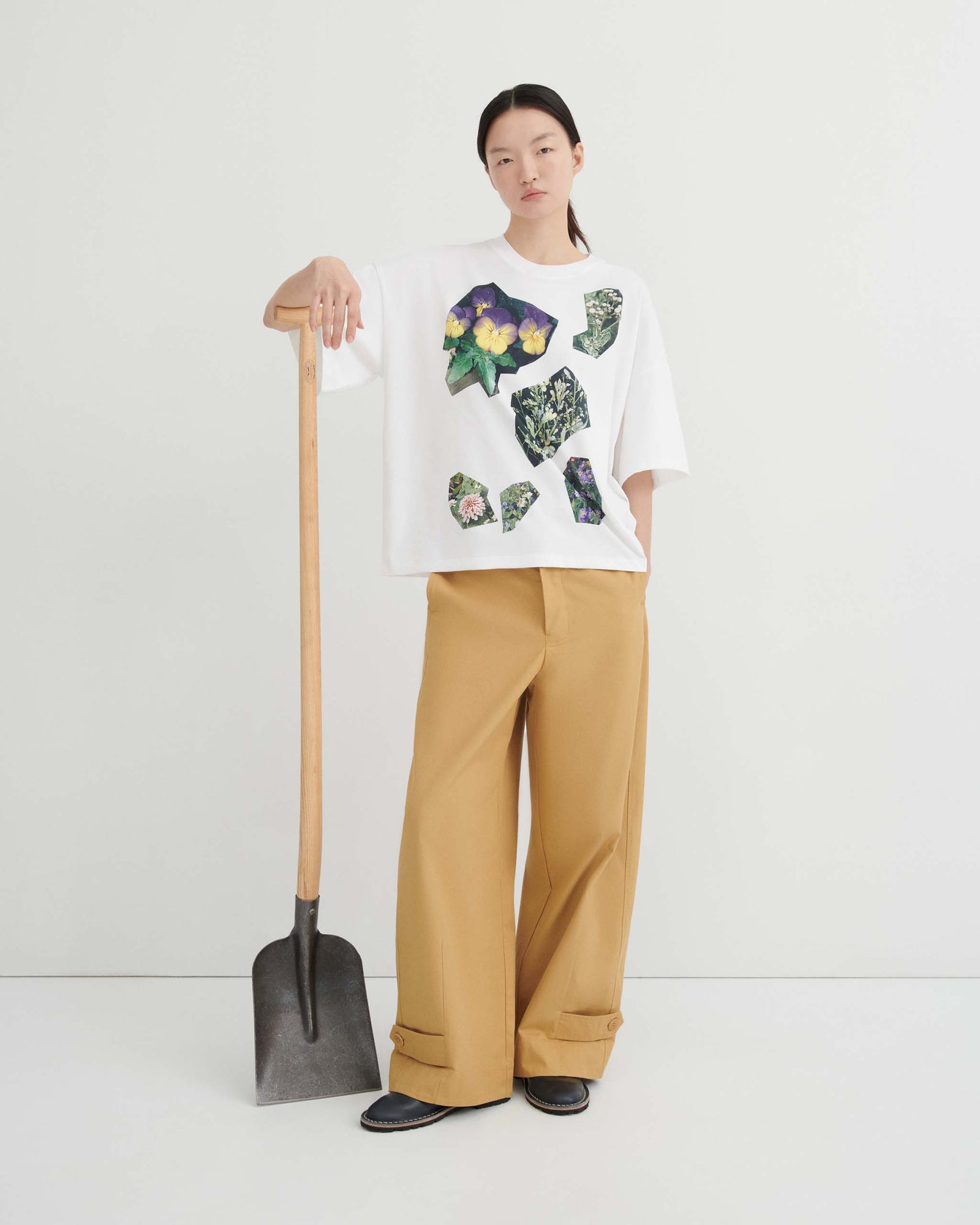 A person wearing a white t-shirt featuring a collage of flower and plant illustrations in geometric shapes.