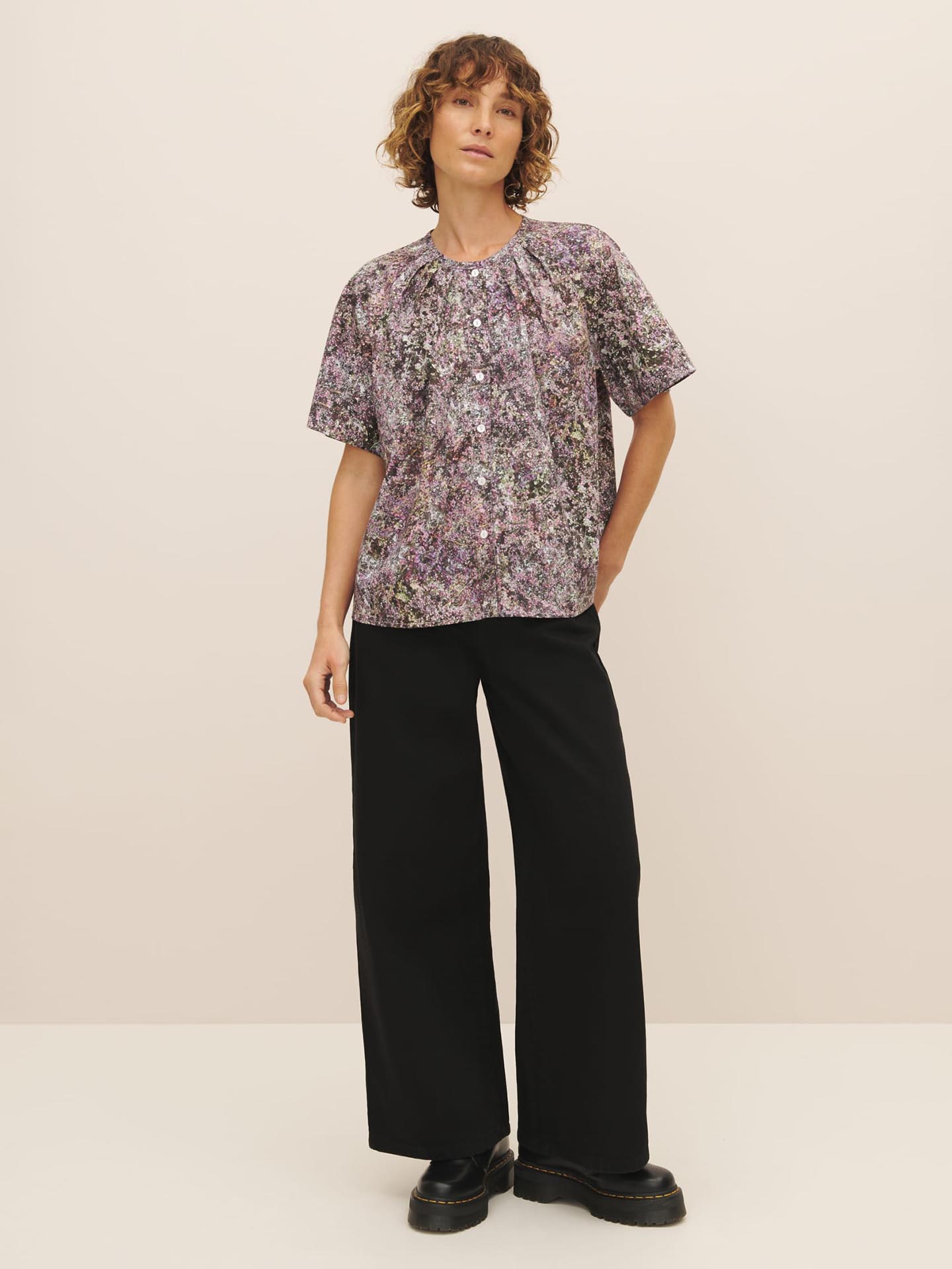 A person wearing a Kowtow Etude Top – Bouquet paired with black trousers and black shoes against a neutral background.