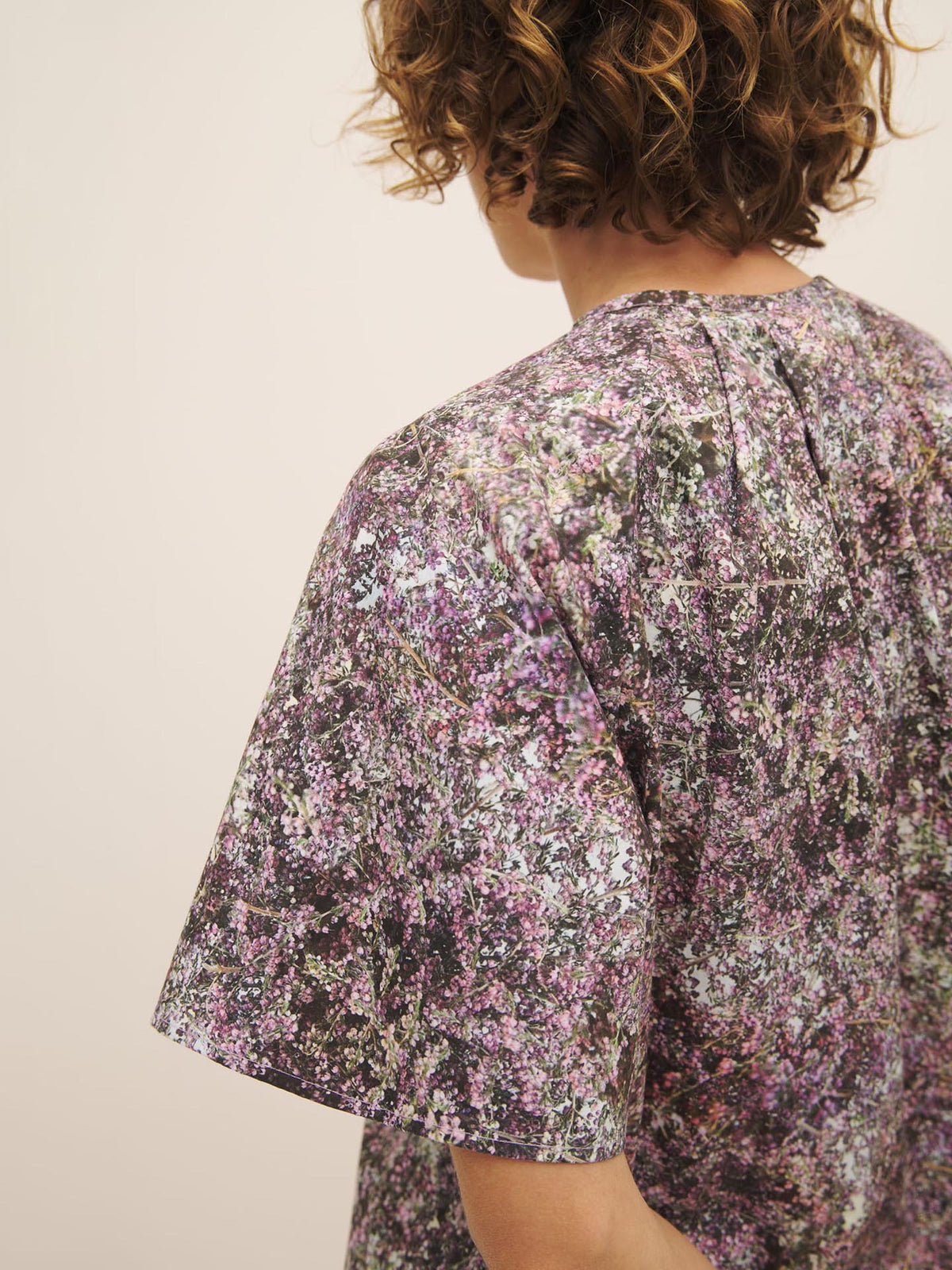 Person wearing a floral-patterned Kowtow Etude Top – Bouquet with an oversized fit, focusing on the shoulder and back area.
