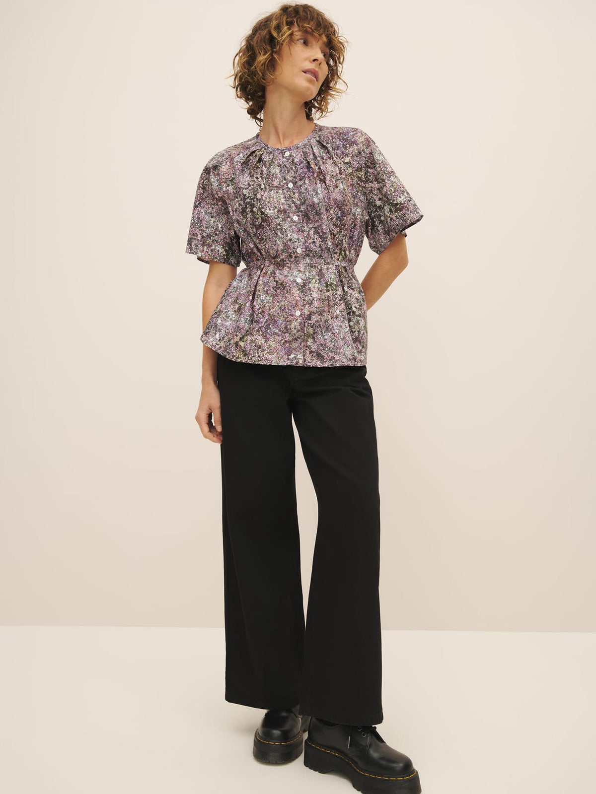 Woman posing in a Kowtow Etude Top – Bouquet with an oversized fit and black trousers.