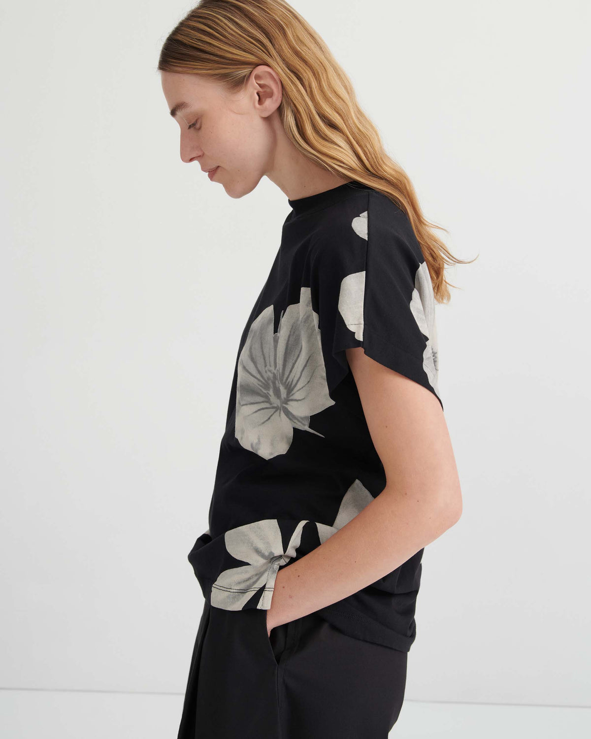 Side view of a person wearing a black short-sleeved t-shirt with a large white floral print.