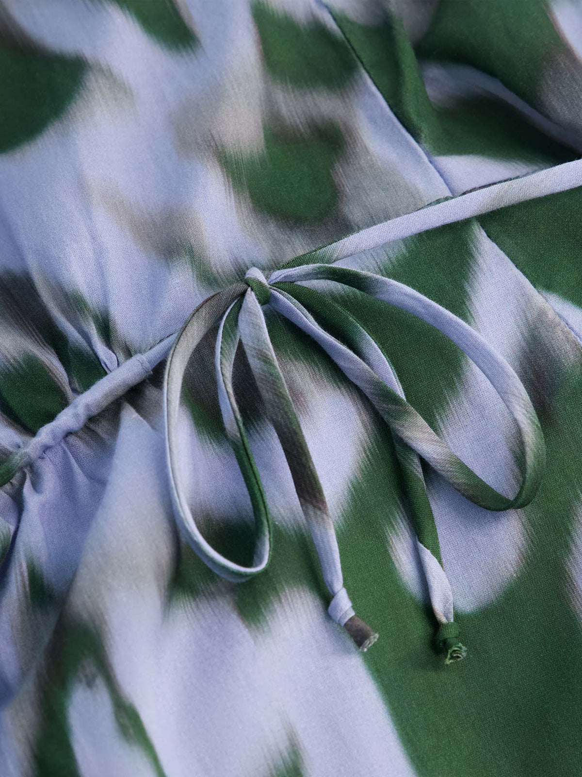 Close-up of the Illustrate Dress – Misty Floral in standard fit, featuring a green and light blue floral-print fabric with a drawstring tied in a simple bow at the center.